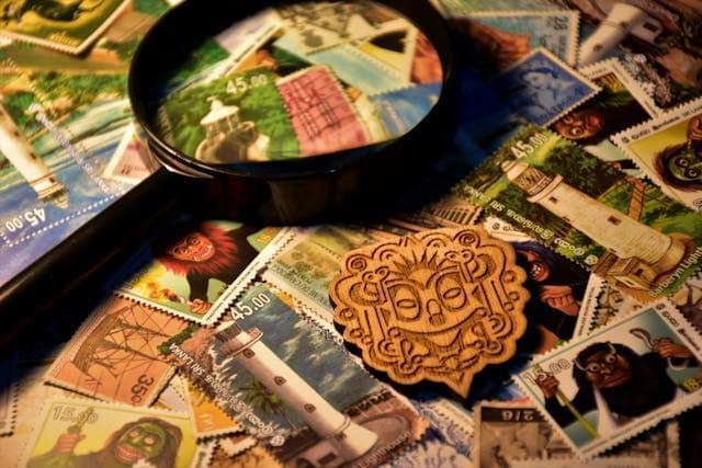 Lupa leżąca na dużej ilości róznokolorowych znaczków pocztowych